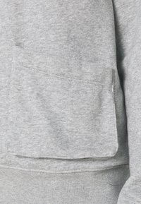 Gray sweatshirt fabric with a soft, textured surface. Features a large front pocket, neatly stitched edges, and a relaxed fit design.