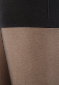 Schwarze und beige strukturierte Strumpfhosen mit einem einfarbigen schwarzen Oberteil und einem kontrastierenden beigen Unterteil, das ein gitterartiges Muster aufweist.