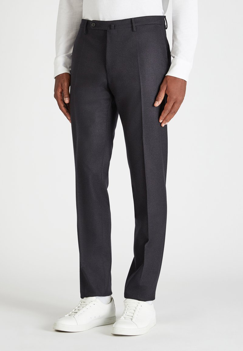 Ciemnoszare spodnie o dopasowanym kroju z gładką fakturą, płaskim przodem i bocznymi kieszeniami, zestawione z białymi trampkami.