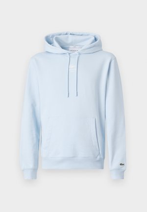 Jasnoniebieska bluza z kapturem, kieszenią z przodu, sznurkiem przy kapturze i małym logo na mankiecie lewego rękawa.