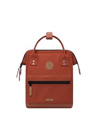 Rust-colored rectangular backpack with top handles, front zip pocket, and visible brand logo on front panel.