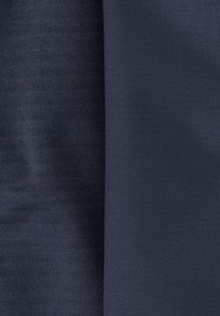 Zwei Abschnitte aus dunkelmarineblauem Stoff; eine Seite hat eine gerippte Struktur, die andere ist glatt mit einem dezenten Rastermuster.