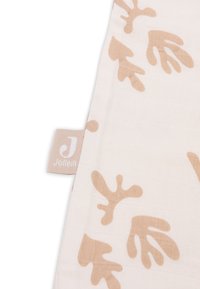 Couverture en muslin de coton couleur crème avec des motifs d'empreintes de mains taupe. Présente une texture en grille carrée et une petite étiquette avec la marque "Jollein".