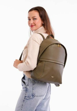Olive green leather backpack with gold hardware; rounded shape, textured surface, one front pocket, worn by a person with light clothing.