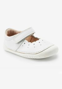 Białe skórzane buty typu Mary Jane z rzepem, falbaniastymi krawędziami, perforowanymi serduszkami, miękką wyściółką i białą gumową podeszwą.
