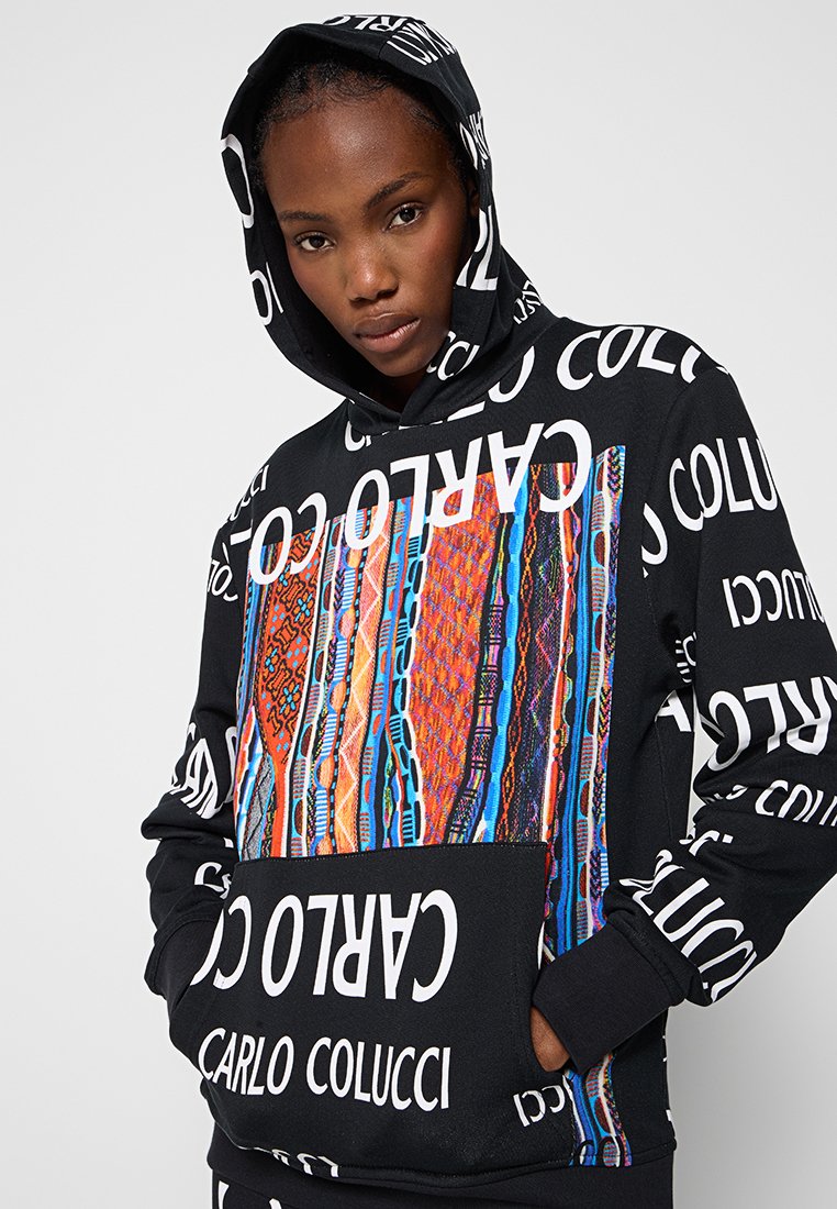 Sudadera negra con una gran inscripción en blanco y un diseño colorido en la parte frontal. Incluye un bolsillo delantero y una capucha con cordón.