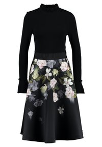 Zwart langemouwen jurk met een gerimpelde kraag en een rok met bloemenpatroon, met roze, grijze en groene bloemen op een zwarte achtergrond.