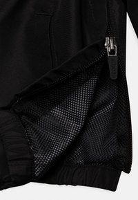 Zwarte jas interieur met meshvoering, voorzien van een ritssluiting en elastische manchetten. Het materiaal lijkt glad en duurzaam met een subtiele textuur.