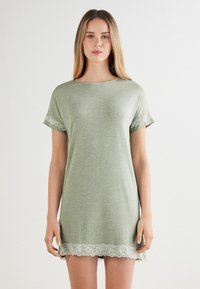 Vestido verde de manga corta en tejido suave, con un escote redondeado y un delicado encaje en las mangas y el dobladillo. Diseño simple y de corte relajado.