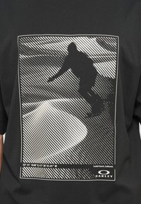 Μαύρο μπλουζάκι με λευκό γραφικό ενός σκέιτερ, με διαγώνιες γραμμές και συντεταγμένες στο κάτω μέρος. Υφασμάτινη βαμβακερή σύνθεση με υφή.