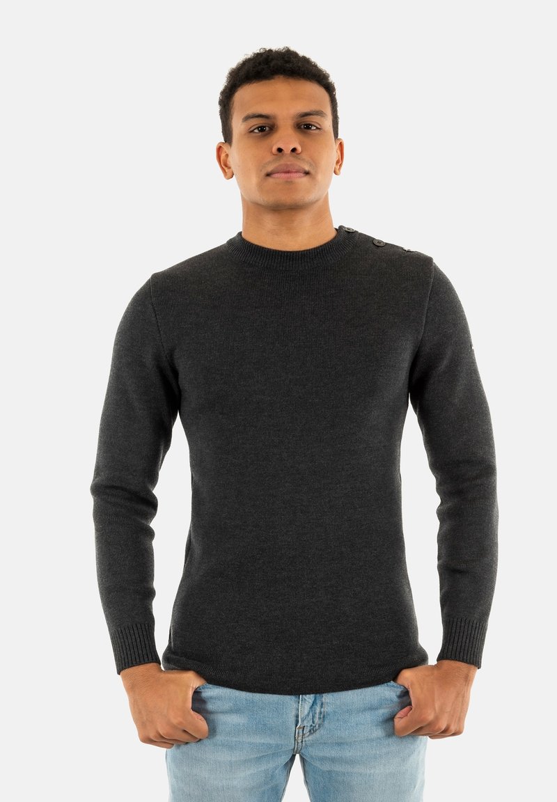 Maglione grigio scuro con collo rotondo, polsini a coste e quattro bottoni sulla spalla. Indossato sopra jeans azzurri chiari. Texture liscia.