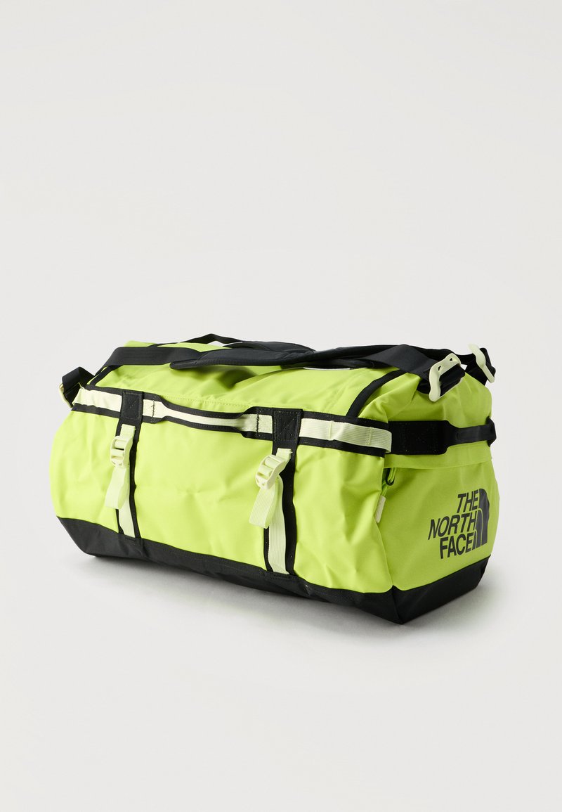 Sac de sport jaune vif et noir avec sangle d'épaule ajustable et sangles latérales à boucle, arborant le logo "The North Face" sur le côté.