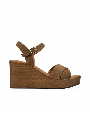 Sandalia de cuña de ante marrón con tira en el tobillo y hebilla, con un tacón de plataforma de madera texturizada.