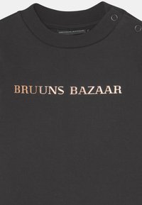 T-shirt de algodão preta com decote redondo, detalhes em botão de pressão no ombro e texto em metalizado rosa dourado "BRUUNS BAZAAR".