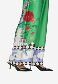 Zelená sukně s květinovým a vázičkovým motivem, zdobená geometrickým černobílým lemem. Kombinováno s černými botami na jehlovém podpatku.
