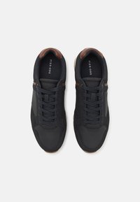 Black athletic shoes with a smooth synthetic upper, brown leather accents, lace-up design, and a textured, rubber sole.