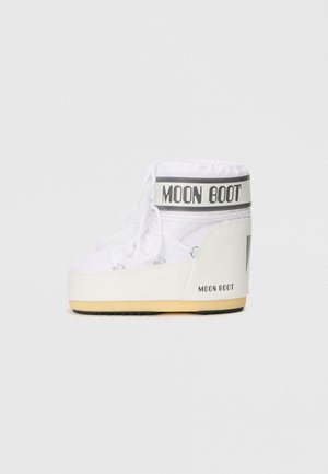 Cizmă albă Moon Boot cu vârf umplut, închidere cu șireturi și talpă din cauciuc. Are o bandă logo neagră și gri la gleznă. Design simplu, rotunjit.