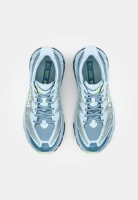 Light blue running shoes with a breathable mesh upper, textured accents, flat laces, and a cushioned sole. Green logo detail present.