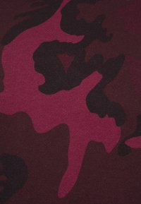 Tessuto mimetico color marrone scuro con motivi astratti in rosa scuro e nero, realizzato in una miscela di cotone testurizzato, che mostra un materiale morbido e traspirante.