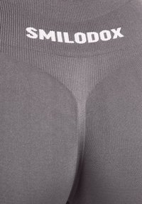 Leggings de sport gris à texture côtelée, avec un logo blanc "SMILODOX" à la taille et une coupe ajustée.