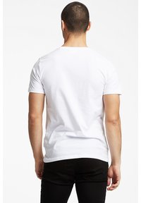 Lyhythihainen valkoinen puuvillapaita, jossa on pyöreä pääntie. Sileä tekstuuri, istuva muotoilu, näkymä takaa ilman näkyviä logoja tai kuvioita.