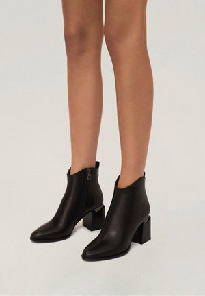 Black leather ankle boots with a pointed toe, zip closure on the side, and block heel; smooth texture with minimal detailing.