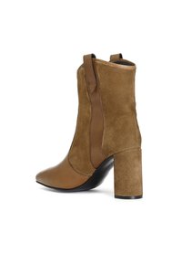 Stivaletto marrone alla caviglia con punta a mandorla, realizzato in una combinazione di pelle liscia e suede. Presenta un tacco a blocco e linguette laterali per una facile calzata.