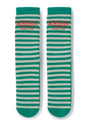 Zielono-beżowe paskowane skarpetki z czerwonym napisem „Stranger Things Benetton” blisko góry na białym tle.