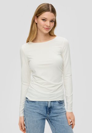 White long-sleeve top with a round neckline, soft texture, and fitted design, paired with light blue denim jeans.