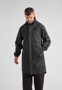 Schwarze wasserdichte Parka mit Kapuze, elastischen Bündchen und Reißverschlusstaschen. Merkmale ein minimalistisches Design und einen geraden, knielangen Schnitt.