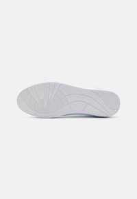 Weißer Sneaker-Sohle mit strukturiertem Gummi, ausgeprägten Sohlenmustern, abgerundetem Zehenbereich und Details im Fersenbereich.