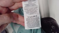Nike tøjetiket, lys teal baggrund, inkluderer plejeinstruktioner og materiale sammensætning: 75% polyester, 25% elastan.