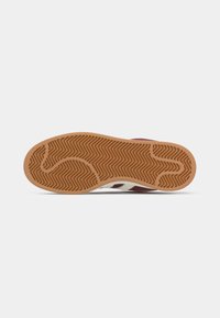 Rød sneakers med hvide sidestriber. Gummisål med et fiskebensmønster og en struktureret, tan mellemsål. Overdelen er glat uden synlig branding.