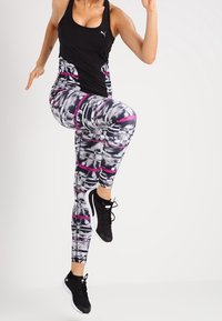 Top sportivo nero e leggings con motivo caratterizzati da una combinazione di tonalità nere, bianche e rosa. I leggings presentano un design geometrico e una forma aderente.
