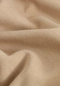 Beige, tekstureret stof med et fint strikkemønster, der hænger blødt med synlige folder og skygger. Glat overflade med subtile variationer.