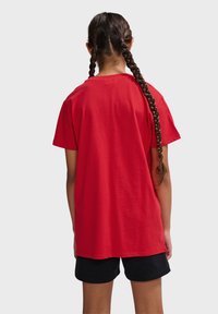 Rød bomulds t-shirt med korte ærmer og rund hals, der har en afslappet pasform og en lige forneden, parret med sorte shorts.