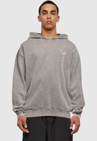 Grå hættebluse med en afslappet pasform, snor i huen og et lille pink flamingo grafik på brystet. Blødt, tekstureret stof.