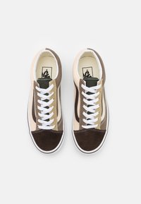 Hnědé a béžové semišové tenisky s bílými tkaničkami, se zeleným akcentem na jazyku a bílou gumovou podrážkou. Klasický model nízkých tenisek.