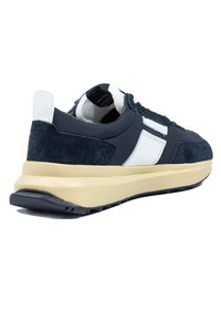 Férfi sportcipők sötét navy kék velúr és textil felsőrészével, fehér szintetikus részletekkel, bézs párnázott középtalppal és fekete gumitalppal.