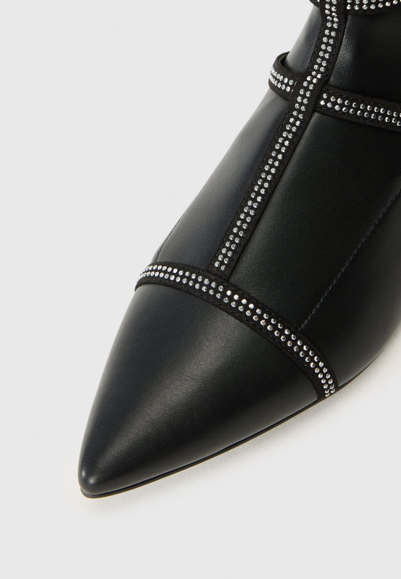 Czarne skórzane buty na szpilce z dekoracyjnymi metalowymi ćwiekami wzdłuż szwów i paska. Gładka tekstura i elegancki design.