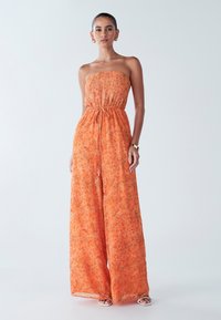 Oranje strapless jumpsuit van lichtgewicht stof met bloemenprint, getailleerde taille en wijde pijpen. Geaccentueerd met een trekkoordsdetail.