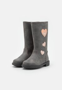 Bottes montantes en simili cuir gris avec des accents en forme de cœur en rose gold sur le côté extérieur et une semelle en caoutchouc texturée.