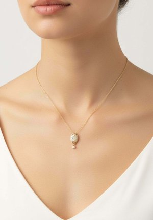 Delicado collar de oro con un colgante en forma de globo aerostático que presenta detalles de perlas y pequeños diamantes, llevado en el cuello de una mujer.