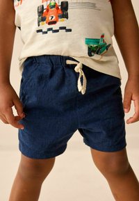Mörkblå shorts i lätt material med elastisk midja och dragsko, med sidofickor och en mjuk yta.