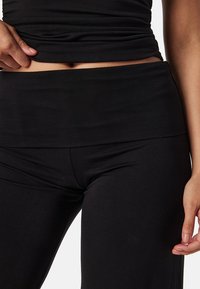 Zwarte stretchstoffen outfit met een geraffineerde top en hoge taille legging, met een gladde, zachte textuur en naadloos ontwerp.