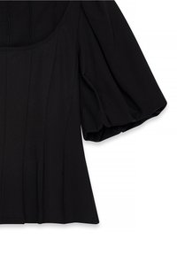 Haut noir à manches courtes avec manches bouffantes et détails de coutures verticales à l'avant et sur le côté.
