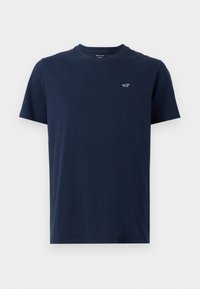 Navyblaues Baumwoll-T-Shirt mit kurzen Ärmeln, rundem Halsausschnitt und einem kleinen Logo auf der linken Brust. Weicher Stoff, klassischer Schnitt.