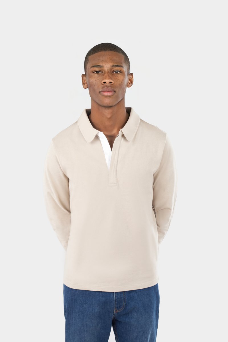 Beige Langarm-Polohemd mit weißer Blende, mit umgeschlagenem Kragen und lockerer Passform, kombiniert mit blauen Jeans.