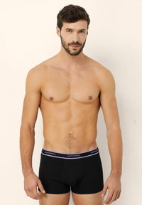 Boxeri scurți negri din bumbac, cu un brâu elastic accentuat cu violet, etichetat "yamamay". Design ajustat, textură netedă și lungime până la mijlocul coapsei.
