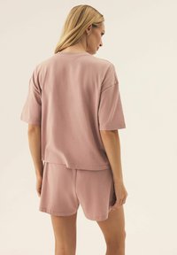 Różowy zestaw odzieży domowej z bawełny, składający się z luźnej bluzki z krótkim rękawem i dopasowanych szortów, o swobodnym kroju i miękkiej teksturze.